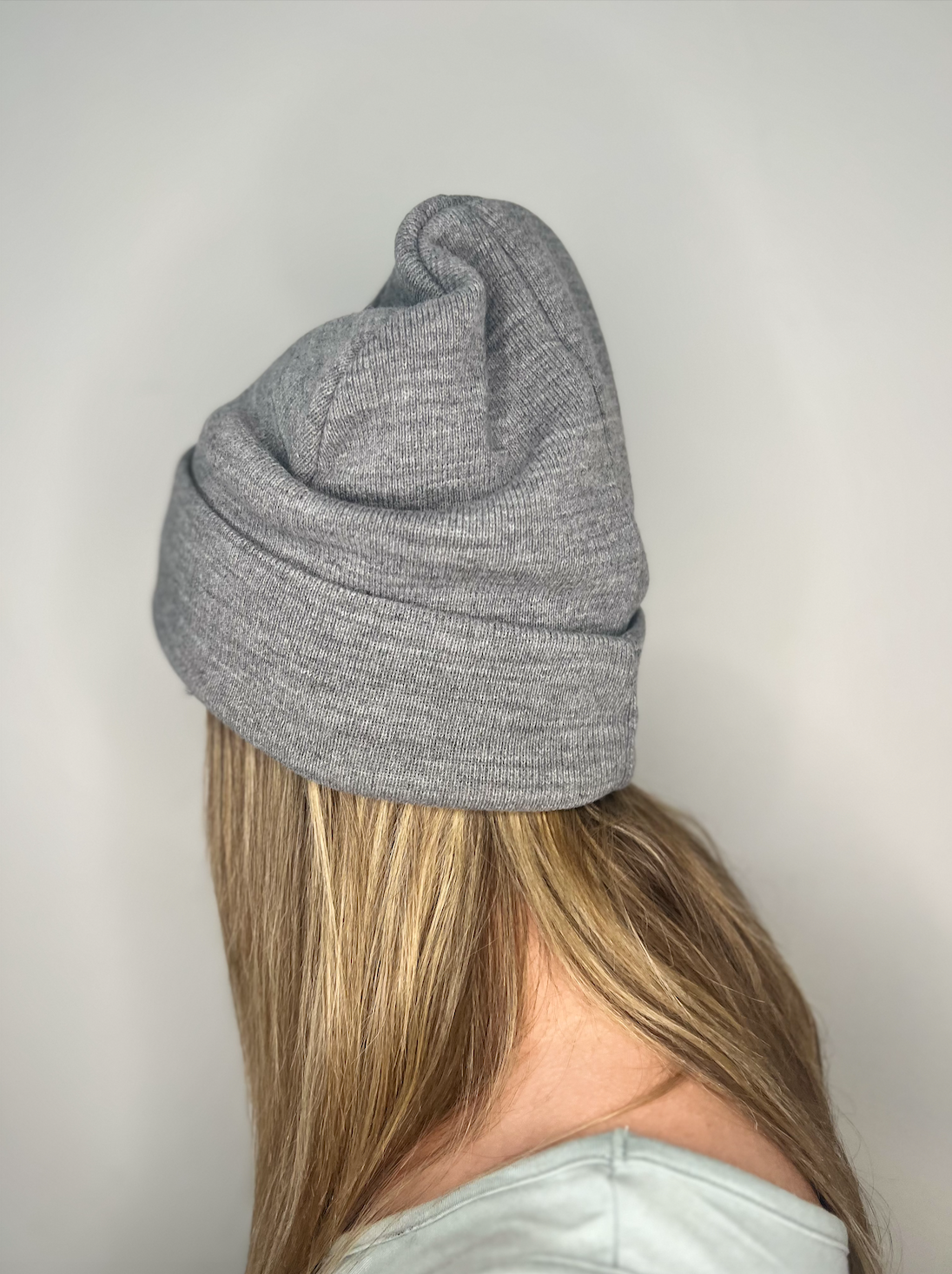 Tuque chinée grise en Polyana, vue de côté, portée par une femme, mettant en valeur la texture chinée élégante et la coupe confortable.