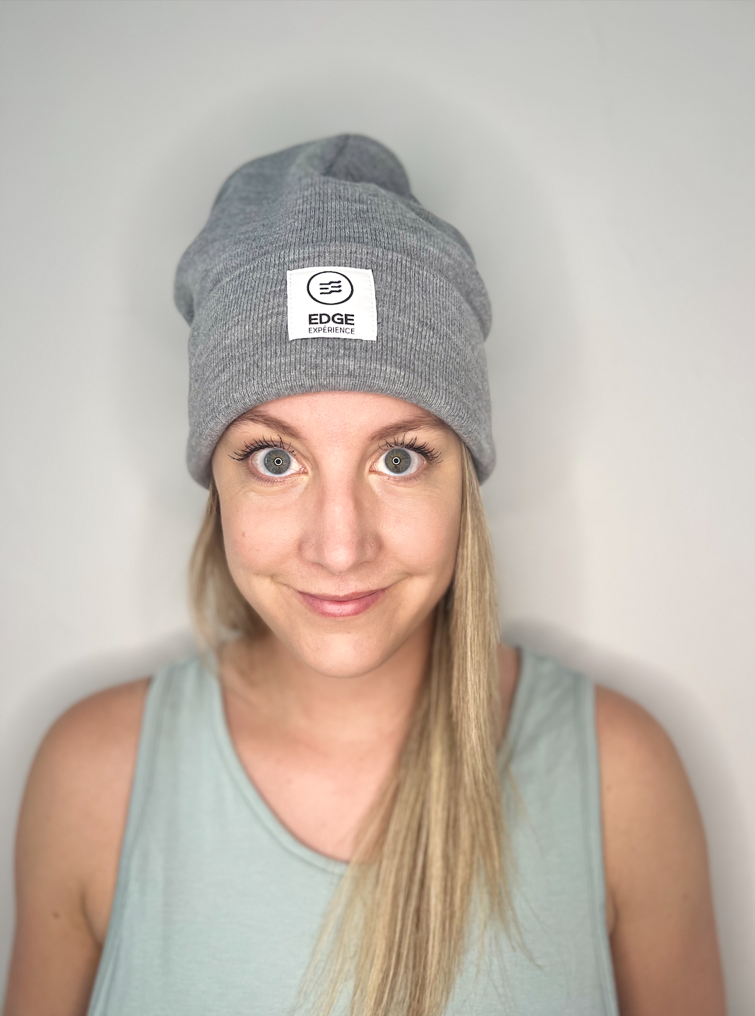 Tuque chinée grise en Polyana, vue de face, portée par une femme, offrant un design en tricot performant et durable, idéal pour la randonnée et la détente.