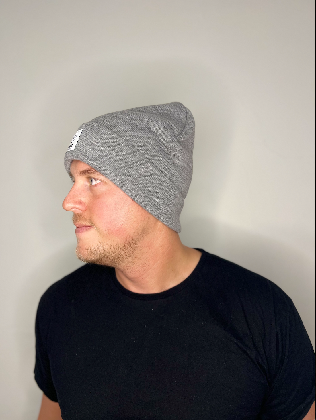 Tuque chinée grise en Polyana, vue de côté, portée par un homme, mettant en valeur la texture chinée élégante et la coupe confortable.