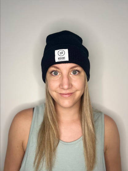 Tuque en tricot gaufré recyclée couleur noire, vue de face, portée par une femme, avec fit profil moyen et mélange durable de laine Mérinos extrafin et Dralon.