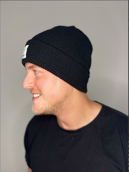 Tuque en tricot gaufré recyclée couleur noire, vue de côté, portée par un homme, mettant en avant les détails du tricot gaufré et la coupe profil moyen.